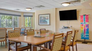 Activity room with table seating, television, and space for games and events at Cornerstone Assisted Living in Plymouth MN.