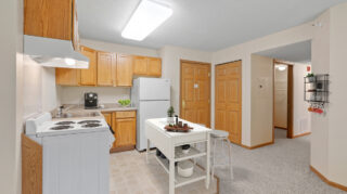 Apartment kitchen with full appliances, cabinets, and dining area at Cornerstone Assisted Living in Plymouth MN.