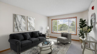 Apartment living room with sofa, chair, coffee table, and large window at Cornerstone Assisted Living in Plymouth MN.