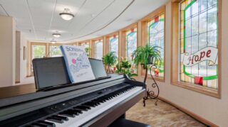Piano and stained glass windows in the chapel at Cornerstone Assisted Living in Plymouth MN.