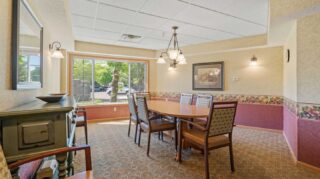 Community dining room with table seating and large window views at Cornerstone Assisted Living in Plymouth MN.