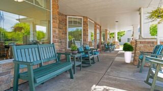 Covered front porch with bench seating and windows at Cornerstone Assisted Living in Plymouth MN.