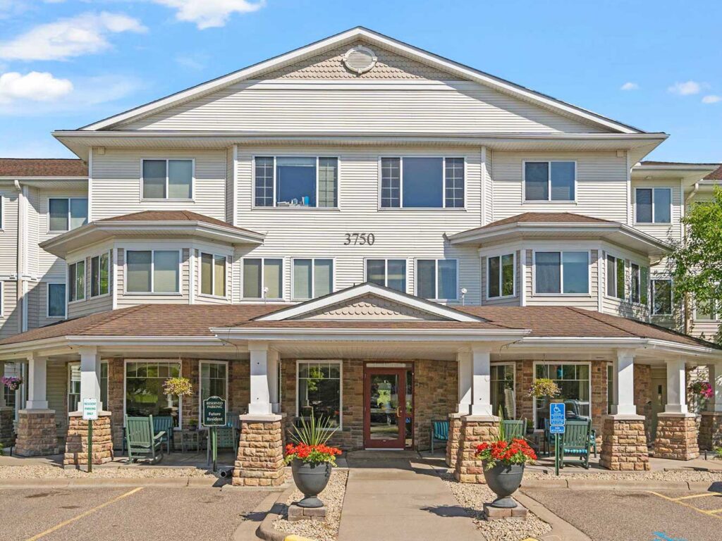 Front exterior entrance with covered porch, seating, and landscaping at Cornerstone Assisted Living in Plymouth MN.