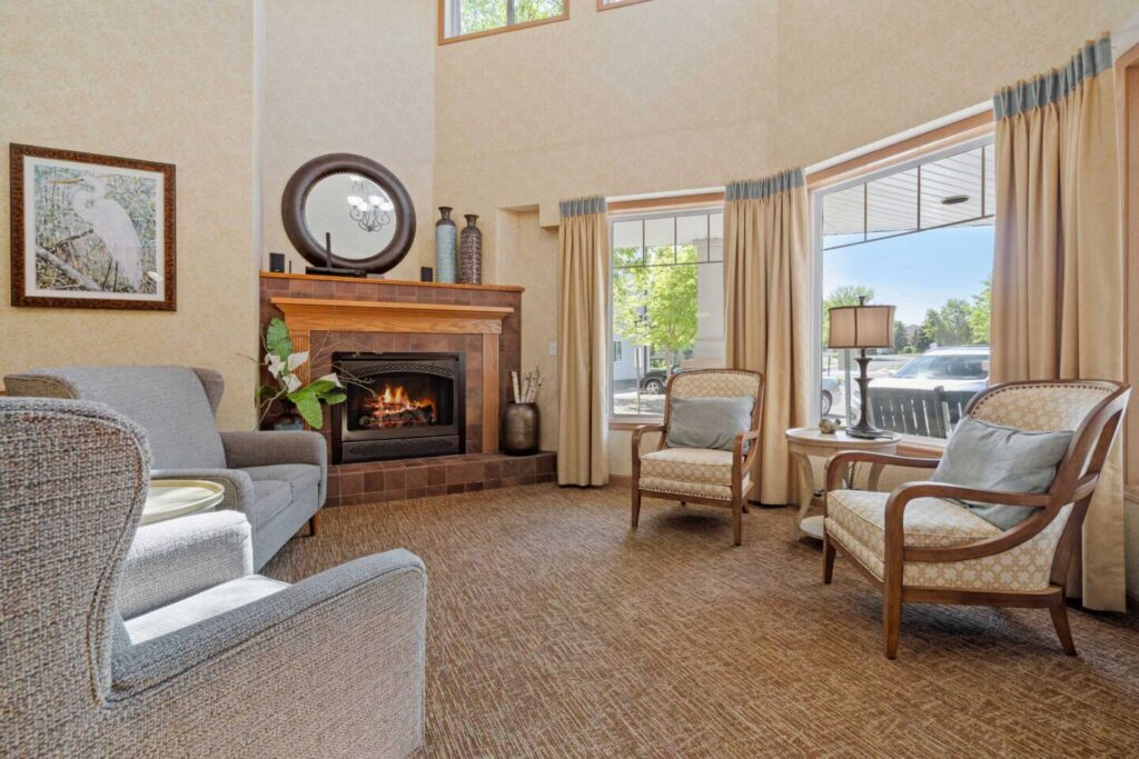 Fireside lobby seating area with fireplace and large windows at Cornerstone Assisted Living in Plymouth MN.
