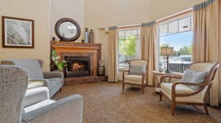 Fireside lobby seating area with fireplace and large windows at Cornerstone Assisted Living in Plymouth MN.