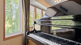 Grand piano near large windows with outdoor views at Cornerstone Assisted Living in Plymouth MN.