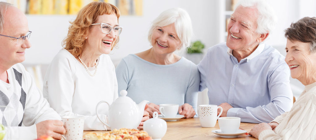 Residents gather around a table and talk during a meal at a community like Cornerstone Independent Living in Plymouth MN.