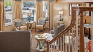 Lobby seating area with chairs, tables, and large windows at Cornerstone Assisted Living in Plymouth MN.