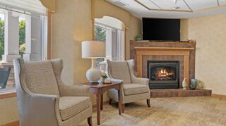 Lounge seating area with fireplace and television at Cornerstone Assisted Living in Plymouth MN.