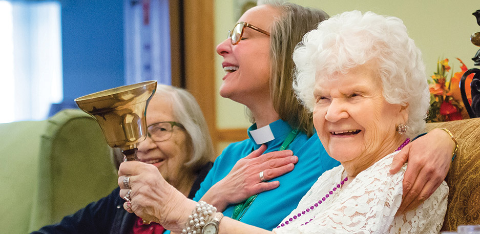 Resident sits with a chaplain or staff member during a supportive moment at a community like Cornerstone Memory Care in Plymouth MN.