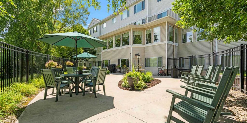 Outdoor patio with seating, umbrellas, and landscaping at Cornerstone Assisted Living in Plymouth MN.