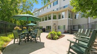 Outdoor patio with seating, umbrellas, and landscaping at Cornerstone Assisted Living in Plymouth MN.