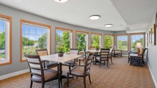 Sunroom with table seating, large windows, and outdoor views at Cornerstone Assisted Living in Plymouth MN.